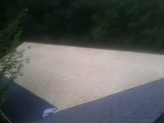 New OSB roof sheathing installed beside an existing shingle roof in Candor