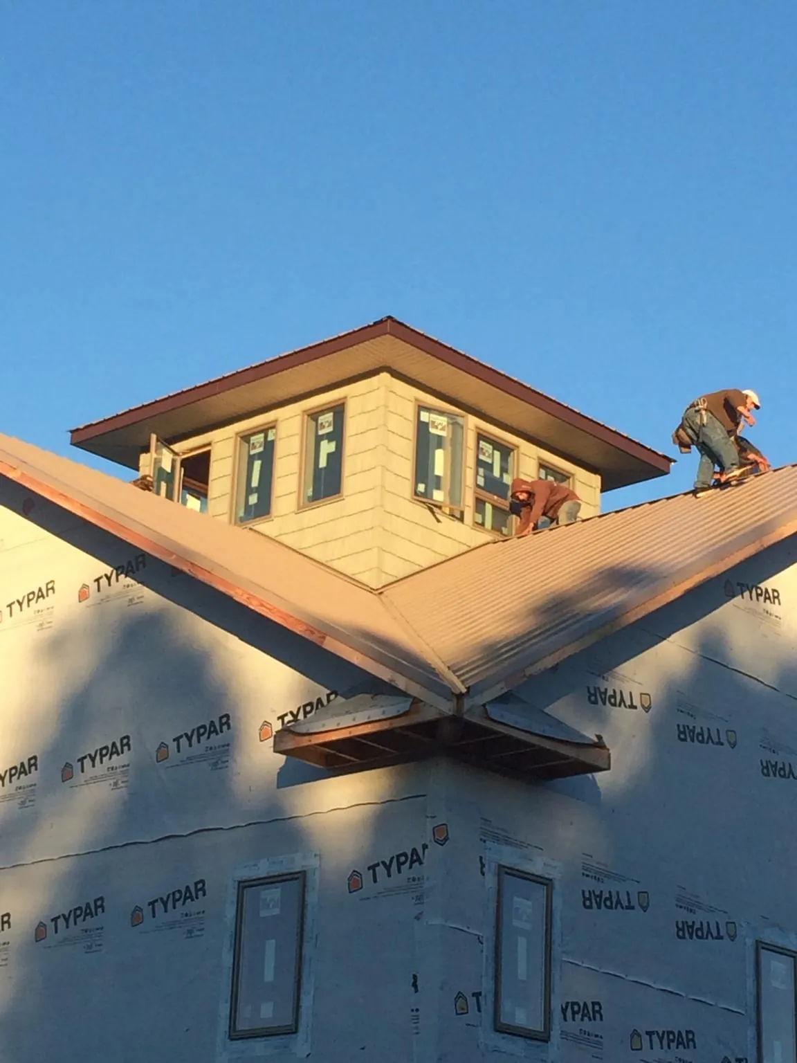 Roofers working around a rooftop cupola on a new metal roof at sunset — Roof Waterproofing in Candor by Roofing Brothers